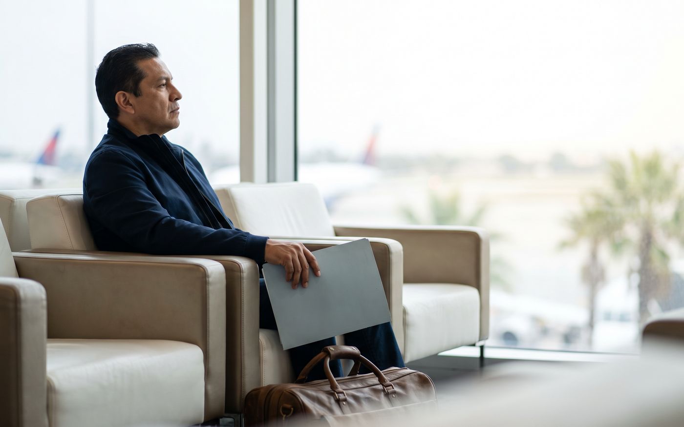 Traveler in airport lounge with folder considering hair transplant medical travel