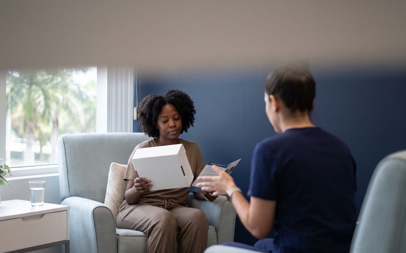 Patient holding plain aftercare kit during crown hair transplant recovery consultation