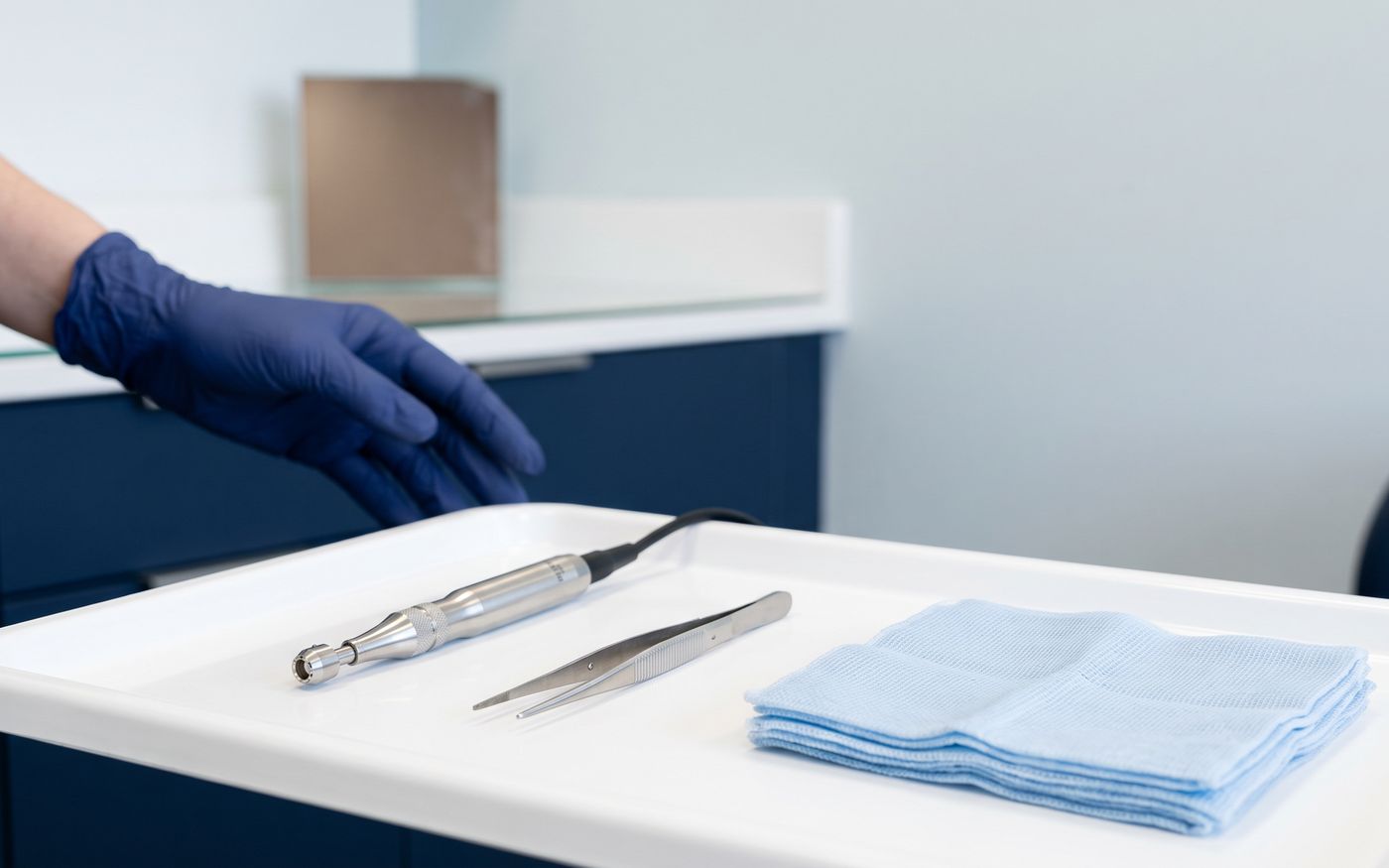 Unshaven FUE instruments with micro-punch and forceps on a sterile tray