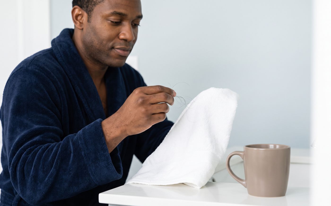 Man calmly examining loose hair on towel after a hair transplant